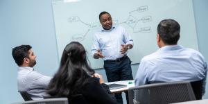 People gathered in a discussion in front of a whiteboard.